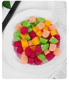 Makroansicht verschiedener Miniatur-Obstwürfel wie Kiwi und Drachenfrucht auf weißem Teller