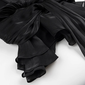 Macro shot of pleated black fabric detail with layered ruffles and silky texture