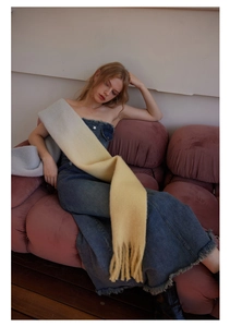 Detail view of long plush scarf with blue and yellow gradient colors and fringe edges