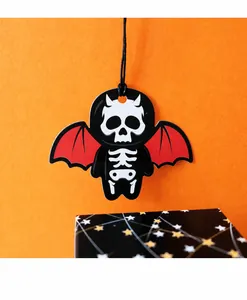 Close-up of Halloween skull tag with red bat wings on festive orange background