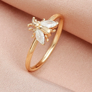 Detailed close-up of a golden bee ring with marquise-cut crystal wings on pink silk fabric