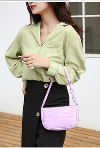 Detail of purple crocodile pattern hobo bag with matching chain strap on female model