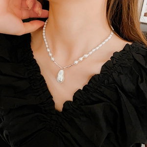 Close-up of a vintage baroque pearl necklace with silver chain on model's neckline