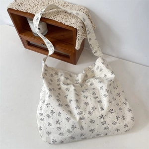 Detailed view of cream canvas crossbody bag with black floral pattern and wide shoulder strap