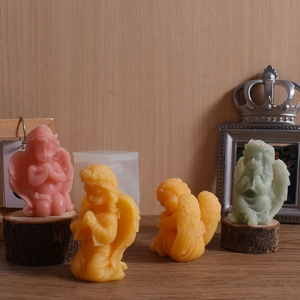 Cupid wing angel silicone molds with finished pastel colored wax candles on wood bases