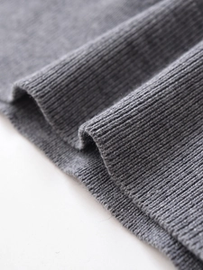 Detailed macro view of the grey ribbed knit texture and cuff stitching on the polo sweater