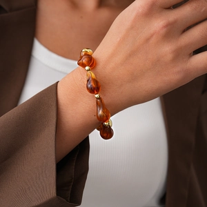 Detail of amber acrylic irregular beads and gold metal spacers on a worn bracelet