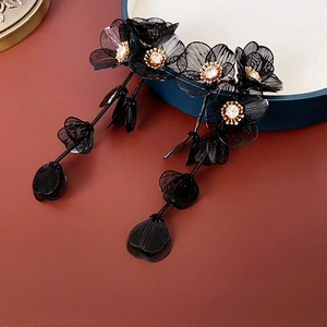 Détail de boucles d'oreilles longues fleurs en résille noire avec cœurs en zircon