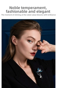 Detail of blue enamel flower brooch with white pearl on a black blazer lapel