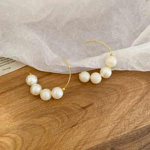 Detailed macro view of French vintage C-shape gold hoop earrings with five white pearls