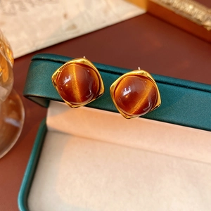 Gros plan de boucles d'oreilles dorées avec résine ambre sur boîte à bijoux verte