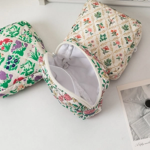 Detail of floral quilted storage bag showing internal compartment and wide zipper opening