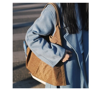 Close-up of brown nylon tote bag featuring unique crinkled texture and wide shoulder strap