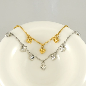 Elegant gold and silver stainless steel heart necklaces displayed in a white bowl