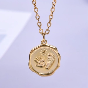 Detailed close-up of golden stainless steel necklace with baby hand and footprint pendant