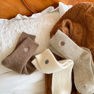 Detailed close-up of thick winter socks with rose embroidery in brown and beige tones