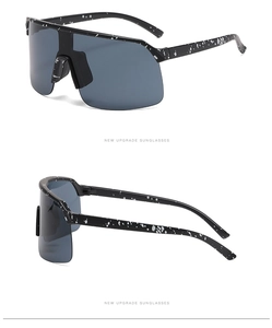 Detail view of large frame cycling sunglasses with black splatter pattern and gray lenses