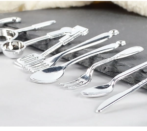 Macro shot of miniature silver kitchen utensils including tiny spoons, forks and pans