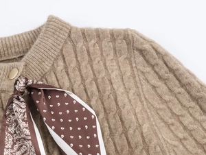 Dettaglio maglione in maglia a trecce color cammello con foulard paisley e bottone oro