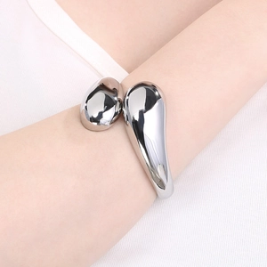 Close-up of sleek irregular silver bangle featuring a teardrop design on model's wrist