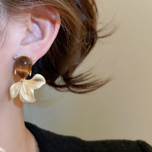 Detail of goldfish earring with brown opal and brushed gold fins on a model