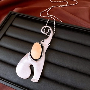 Detail of brushed silver elephant pendant with pink oval inlay on black jewelry tray