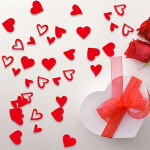 Red heart confetti scattered around a white gift box with roses for wedding decor