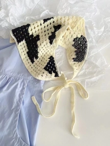 Detail of handmade knit bandana with black and white cow pattern on blue cloth