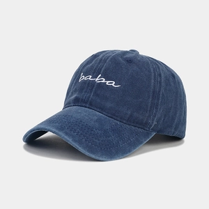 Detailed view of white baba script embroidery on a navy washed cotton baseball cap