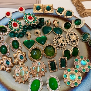 Close-up of vintage gold earrings with green gems and crystals in baroque palace style