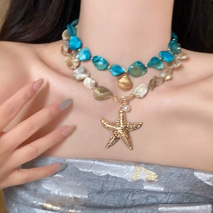 Detail of layered beach necklace featuring blue beads and golden starfish shell pendants