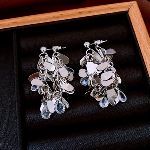 Macro shot of silver tassel earrings with blue teardrop stones in a black velvet jewelry box