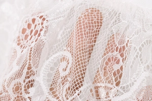 Detailed macro view of white floral embroidery lace fabric with sheer mesh texture