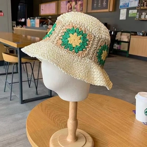Detail showing the intricate floral crochet pattern on a beige summer straw sun hat