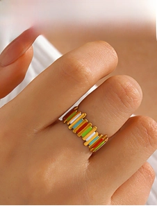 Close-up of golden geometric ring featuring vibrant multi-color enamel inlay on model hand