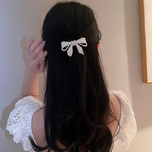 Détail d'une pince à cheveux nœud ornée de strass brillants sur cheveux ondulés