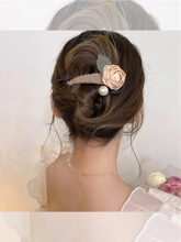Dettaglio del fermaglio per capelli con rosa in raso champagne e perla su uno chignon