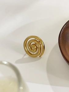 Macro view of a gold-plated spiral ring with polished finish on a wooden display