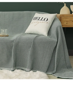 Close-up of sage green waffle weave sofa throw with a white HELLO gorgeous pillow
