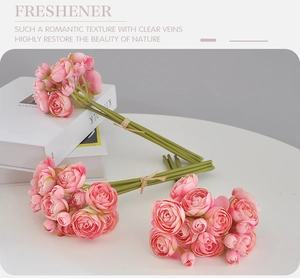 Detailed view of three pink artificial ranunculus bouquets on a white tabletop