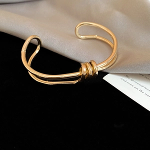 Macro shot of twisted gold cuff bracelet with triple ring knot detail on silk fabric