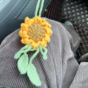 Detailed view of handmade crochet sunflower keychain with vibrant yellow petals and green leaf