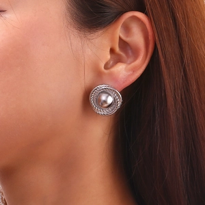 Close-up of vintage round button stud earrings with twisted rope texture on model ear