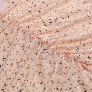Détail de la robe de soirée en tulle rose avec strass rose doré et fleurs en relief