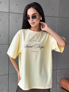Detail of vintage lettering on loose fit cotton t-shirt in pastel yellow hue