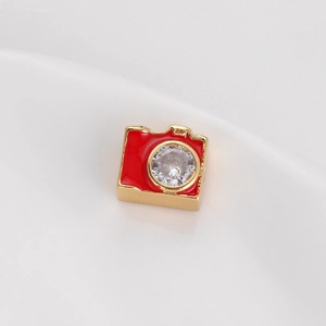 Vista macro di un ciondolo a fotocamera in smalto rosso e oro con zircone incastonato