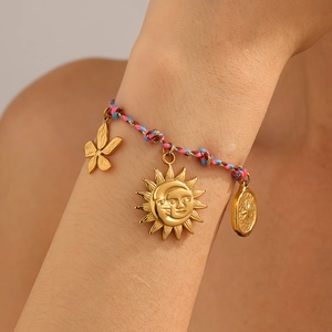 Detail of colorful woven bracelet with gold sun moon and flower pendants on wrist