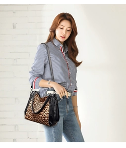 Detail of leopard print tote bag with black leather accents held by a model