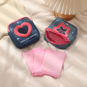 Detailed view of denim makeup bags with heart embroidery and plush ball accents