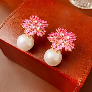 Detailed view of pink flower earrings with crystal petals and dangling white pearls